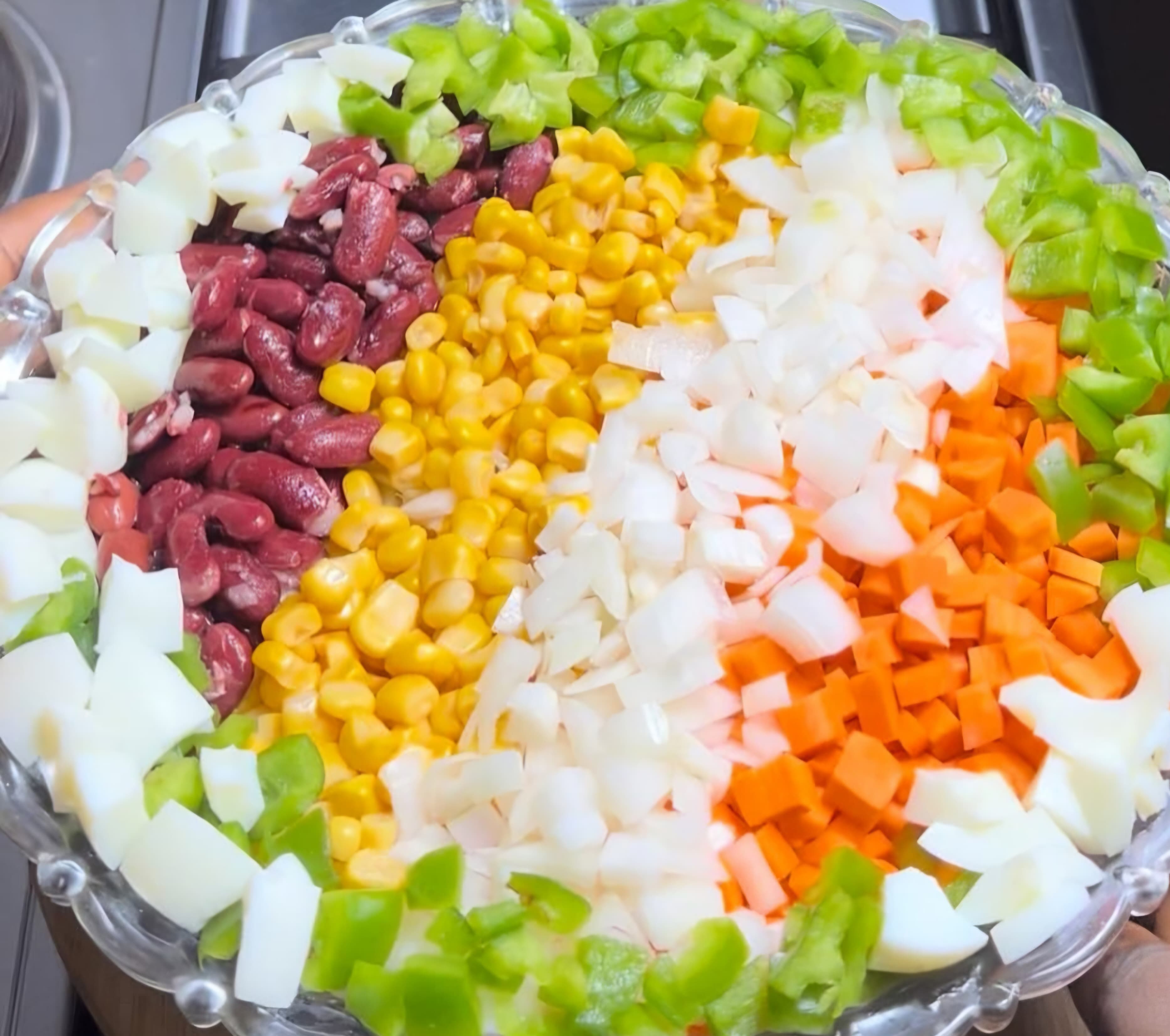 Vibrant salad featuring sections of kidney beans, corn, onions, carrots, and green bell peppers.